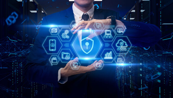 A person in a suit holds a holographic display of cybersecurity icons, including a shield, lock, cloud and data graphs, representing a private 5G network.