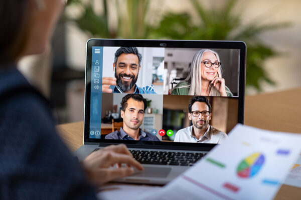 A person in a virtual meeting on a laptop, displaying four colleagues on the screen in separate frames.