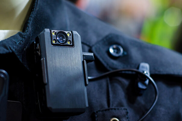 Close-up of a body-worn camera securely attached to a dark uniform shirt.