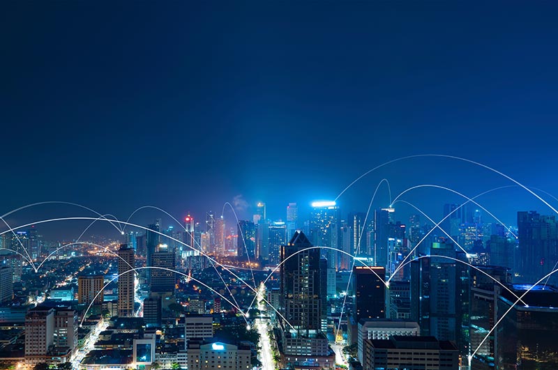 A nighttime cityscape with a network of light trails connecting various skyscrapers.