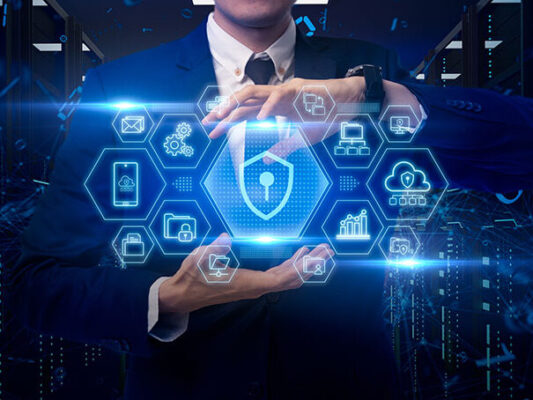 A person in a suit holds a holographic display of cybersecurity icons, including a shield, lock, cloud and data graphs, representing a private 5G network.