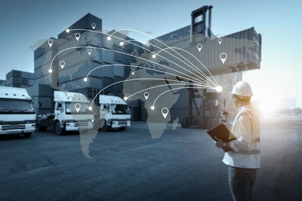 A worker in a hard hat and vest inspects shipping containers, while a digital map overlay of the world with location markers highlights global logistics connections for asset tracking.